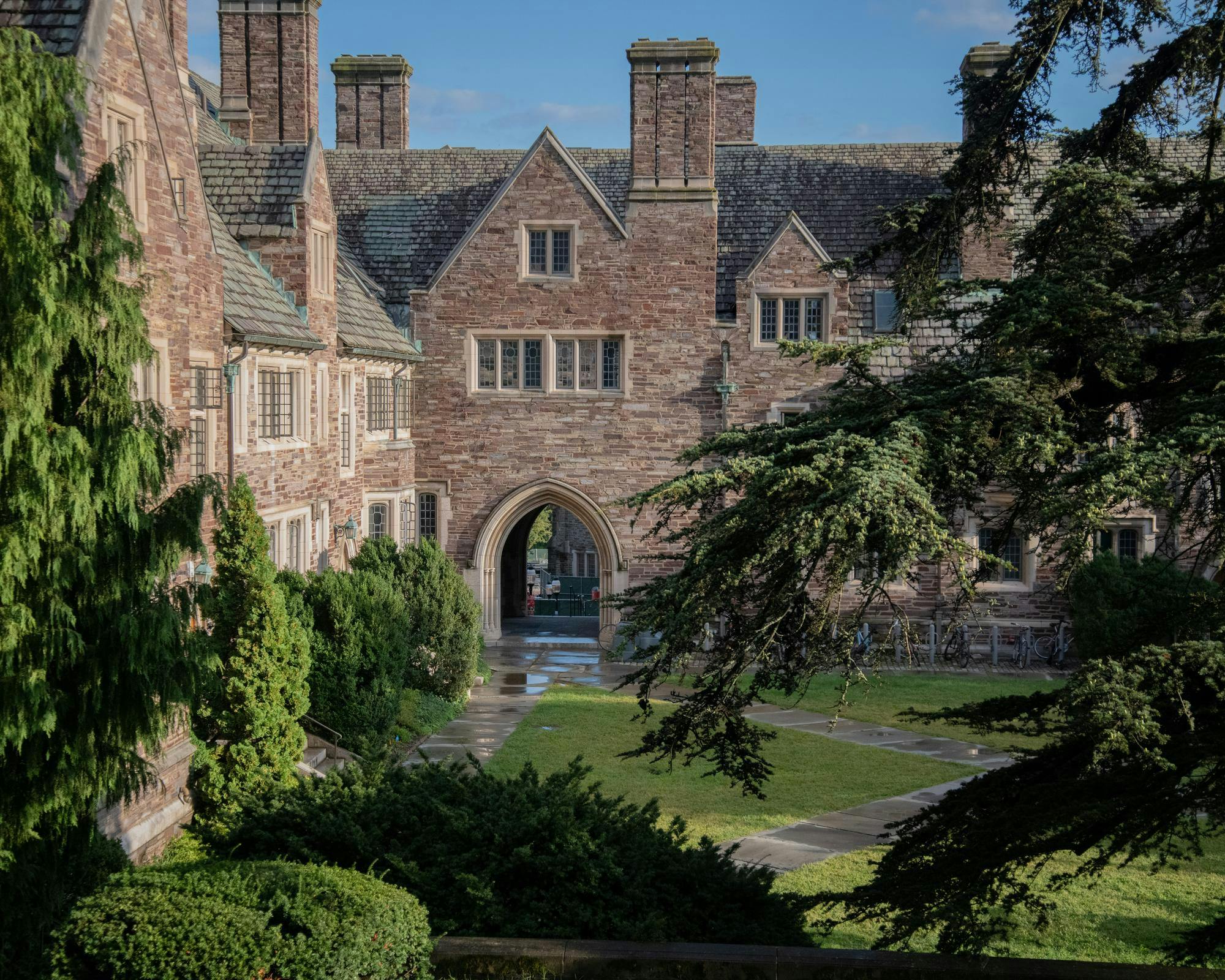 An old stone building overlooks a verdant courtyard after a recent rain.
