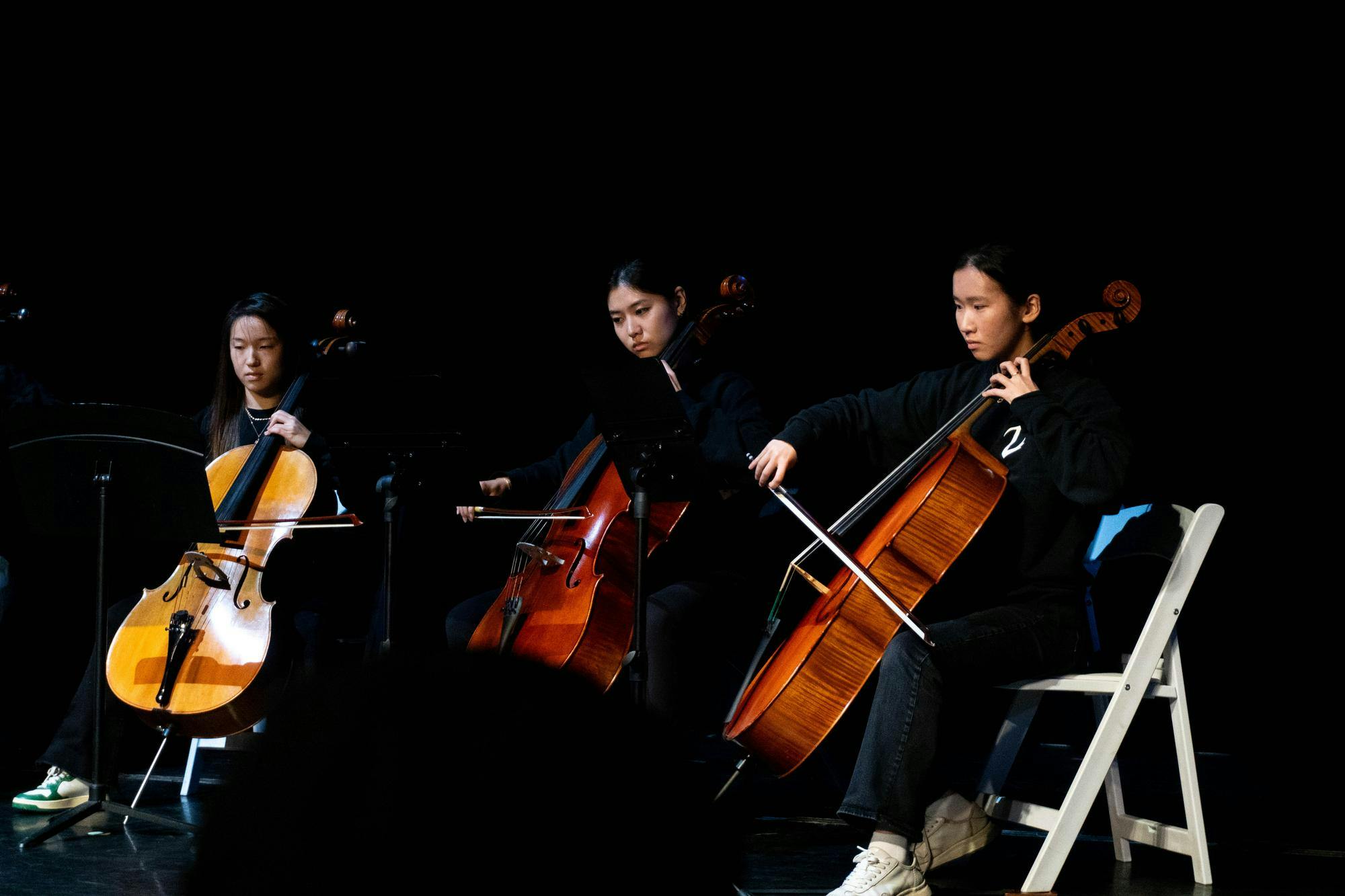 Three seated musicians perform with music stands before them.