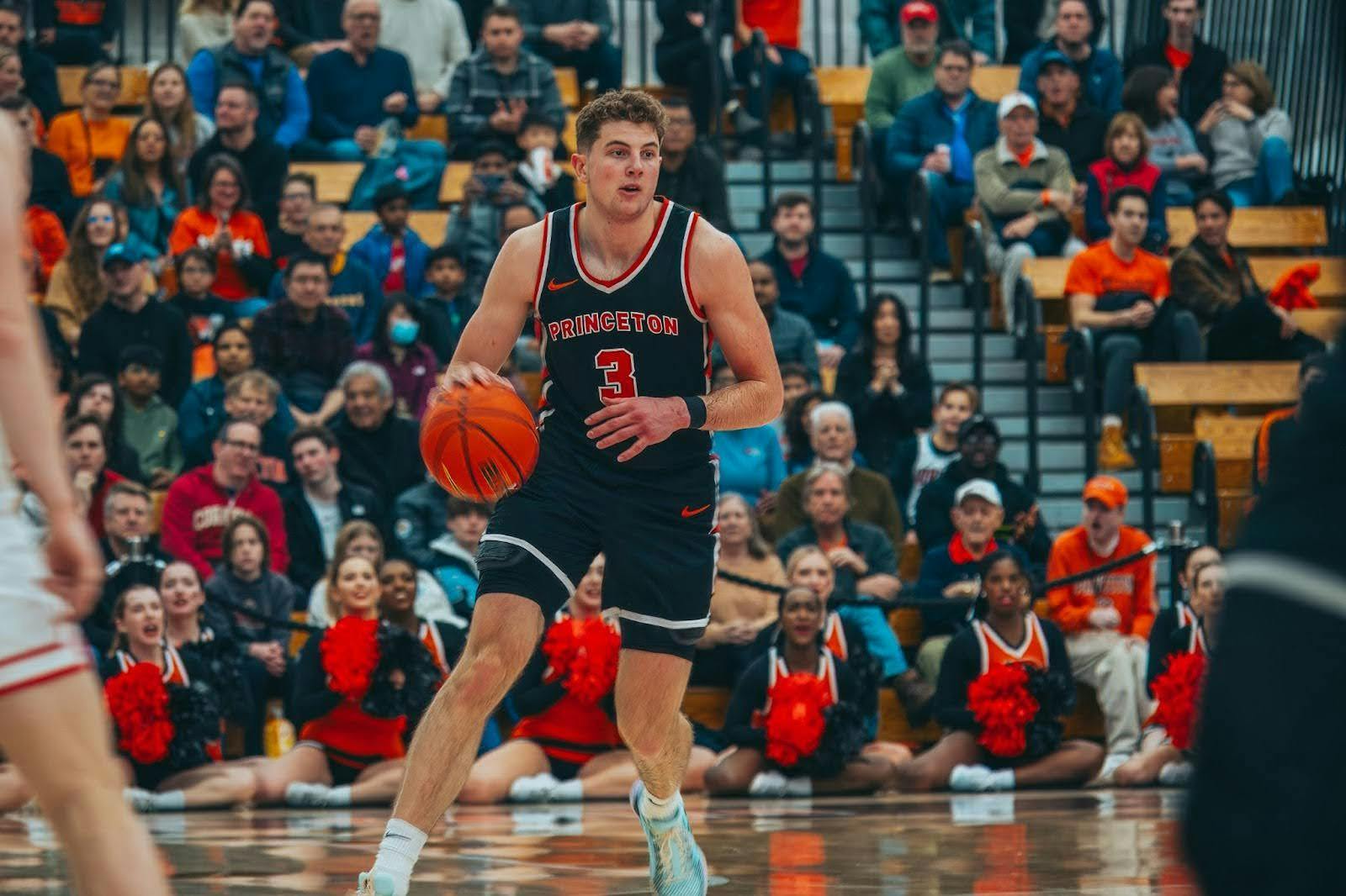 Man in black and orange jersey with an orange number three dribbles a basketball.
