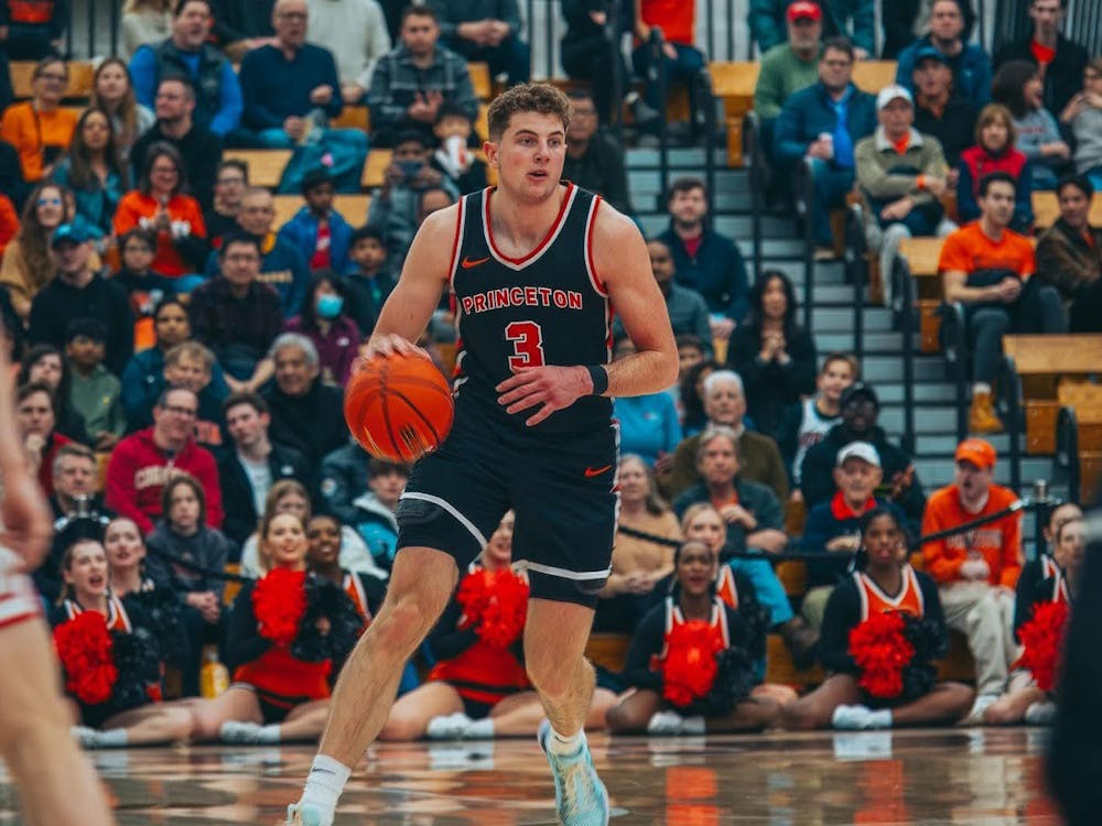 Man in black and orange jersey with an orange number three dribbles a basketball.