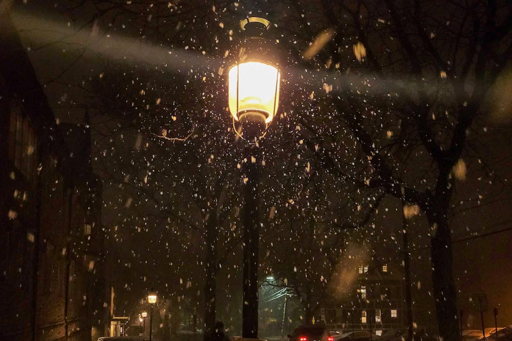 A streetlight shines in the middle amidst a heavy snowfall. 
