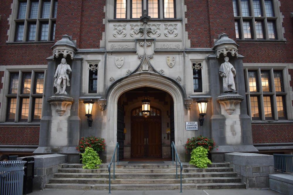 Wooden door surrounded by gothic stone architecture and red brick, with stone stairs leading to the door.