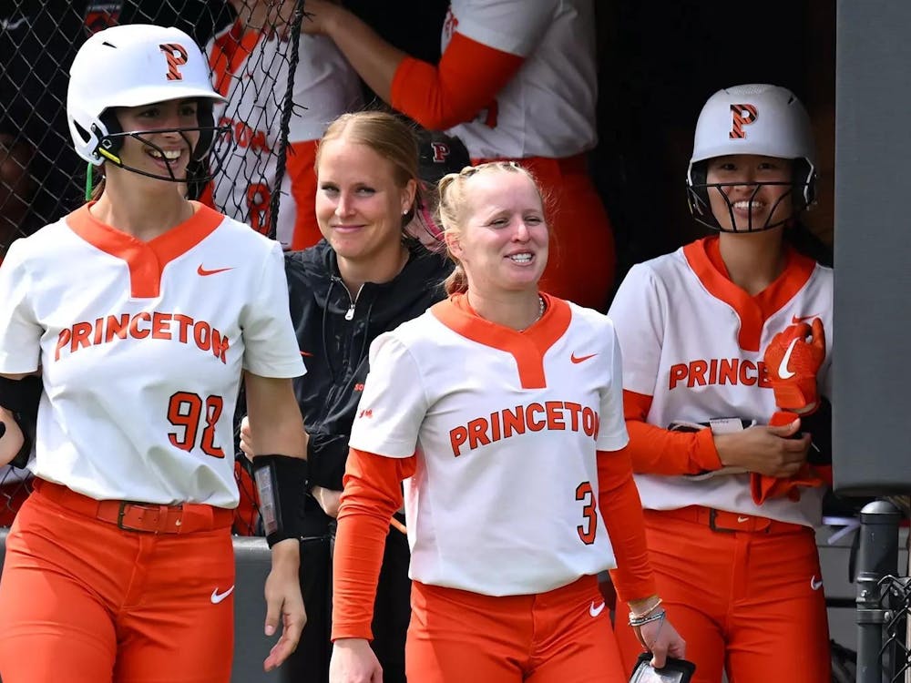 A group of women smiling in the dugout of a baseball field.