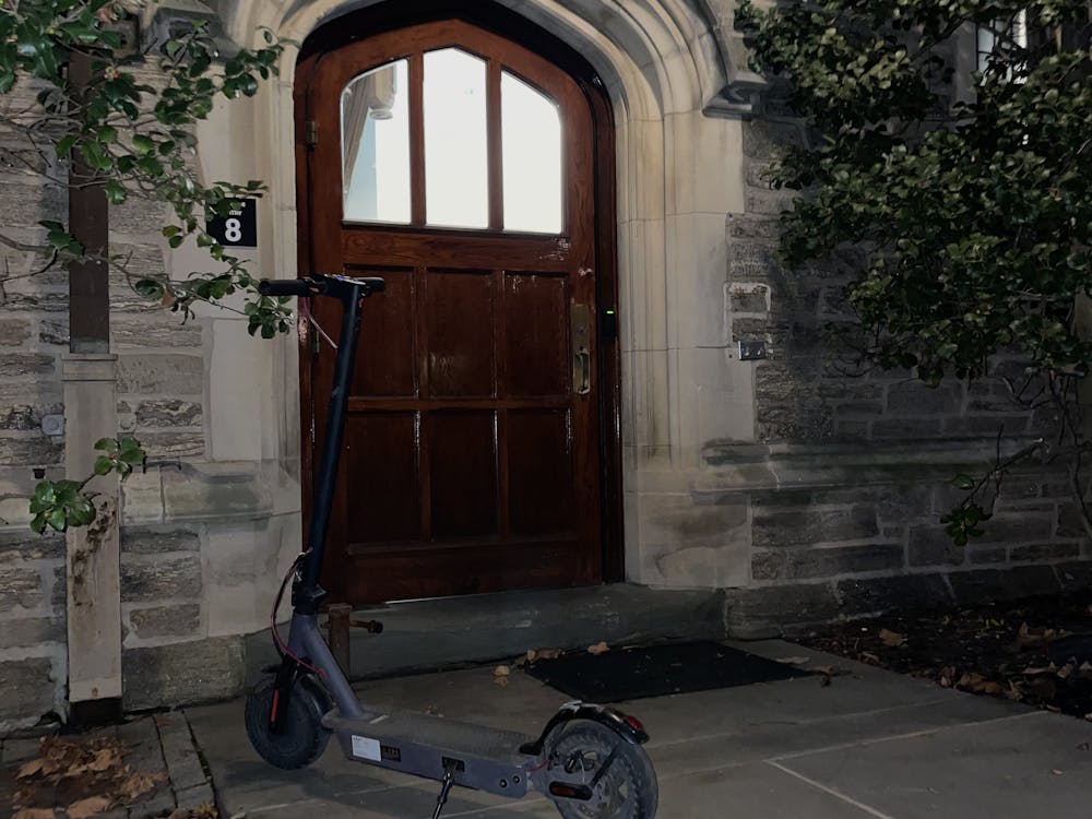 scooter outside a brown door with leaves around it.