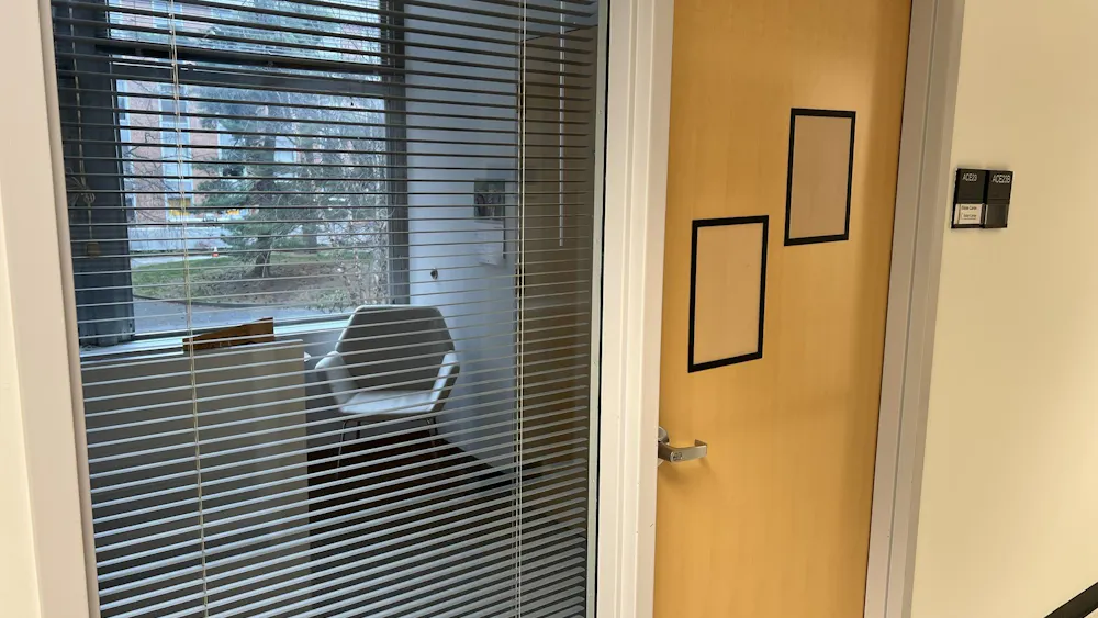 An empty office, with blinds half-shuttered and a closed door.
