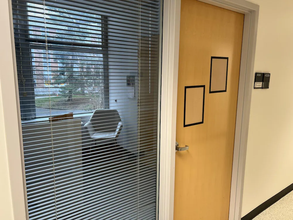 An empty office, with blinds half-shuttered and a closed door.