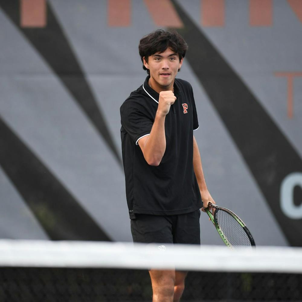 Tennis player in black Princeton shirt pumps fist in celebration.