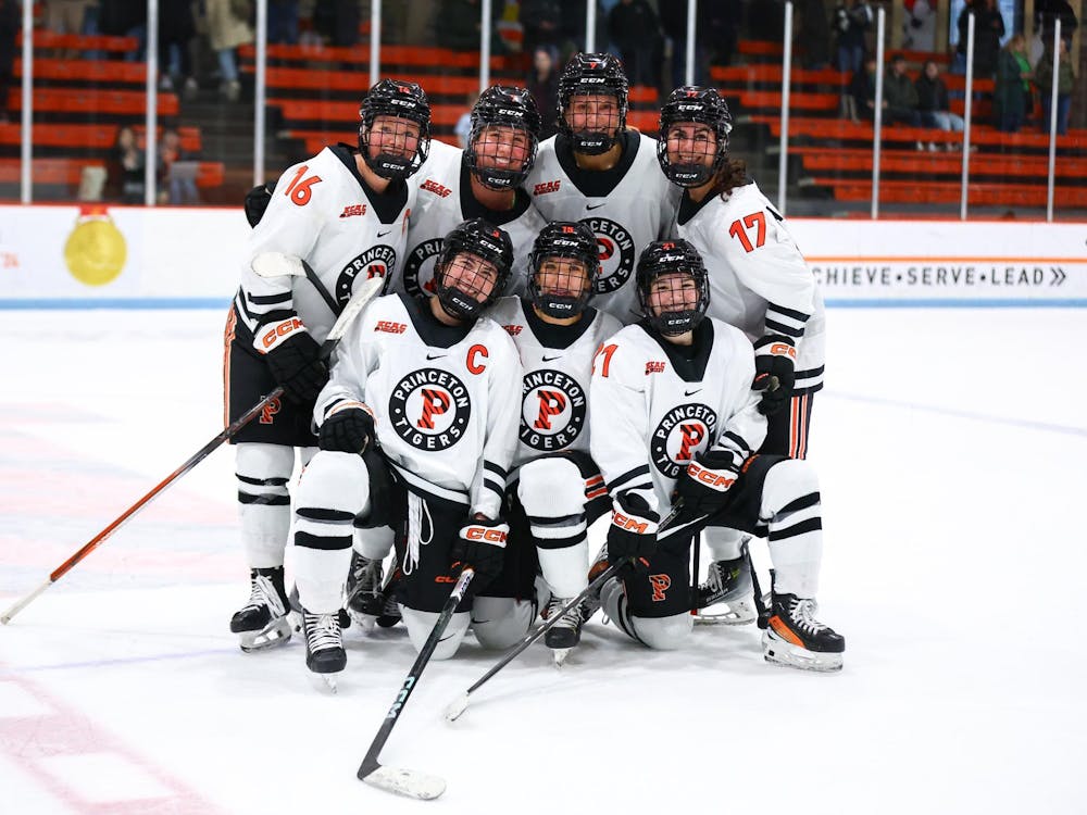 Seven women’s ice hockey players pose on the ice