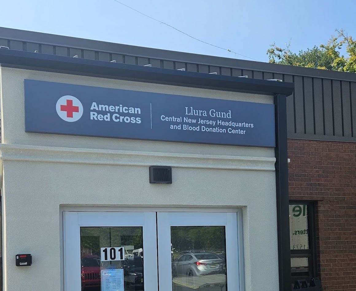 Beige colored building with a sign on top, displaying from left to right: The logo of the American Red Cross, the words American Red Cross, then the words Llura Gund Central New Jersey Headquarters and Blood Donation Center