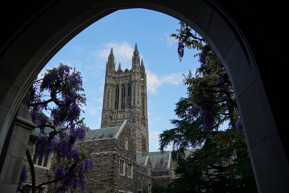 Spire tower in front of a blue sky, as seen from inside an arch.