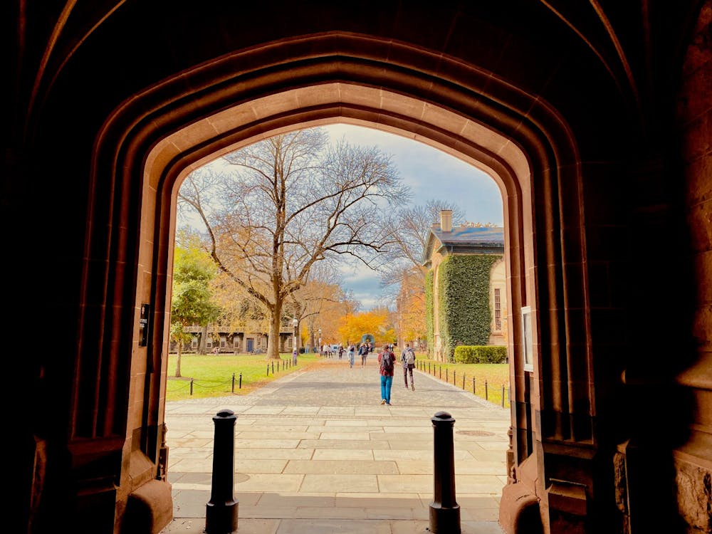 Students walk through an archway during the day.