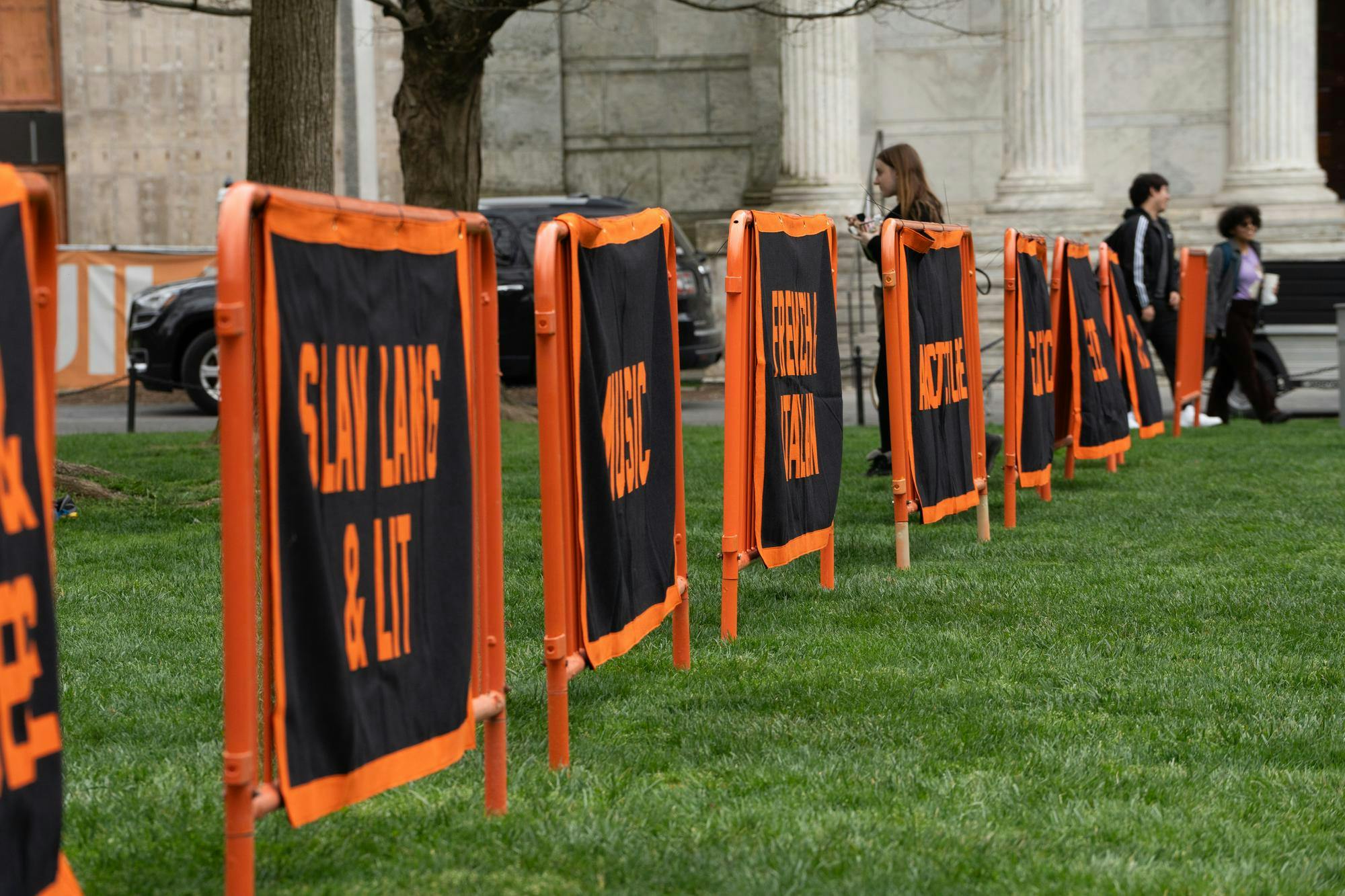 A row of orange and black banners on a green lawn.
