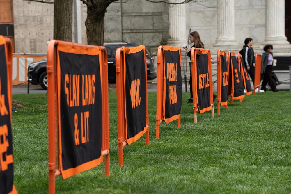 A row of orange and black banners on a green lawn.