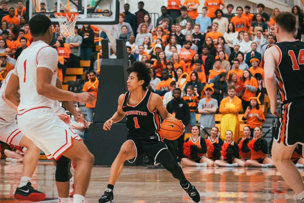 Man in a black jersey on a basketball court looking to make a play  