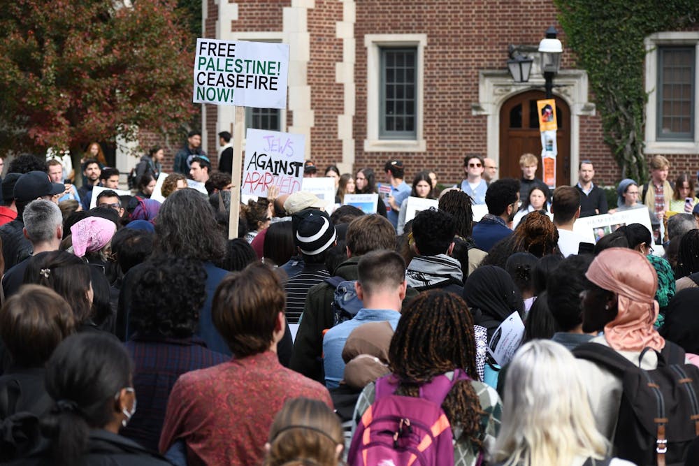 A group of people have their backs to the camera. Some are holding signs reading “Free Palestine! Ceasefire now!” and “Jews against apartheid.”