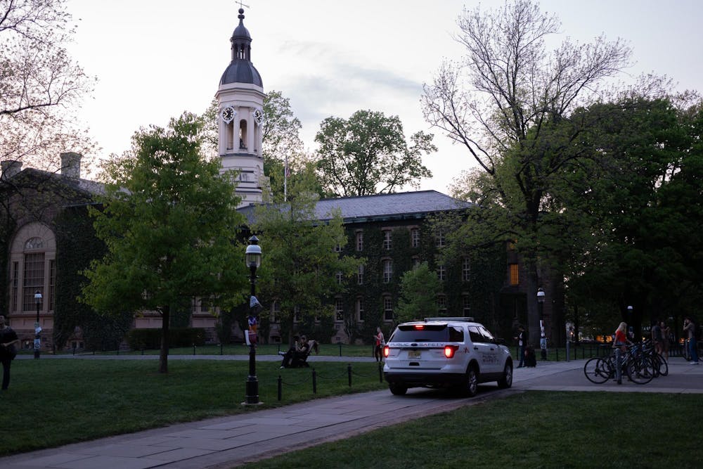 A white police car sits on a walkway next to a grassy field at sunset. 