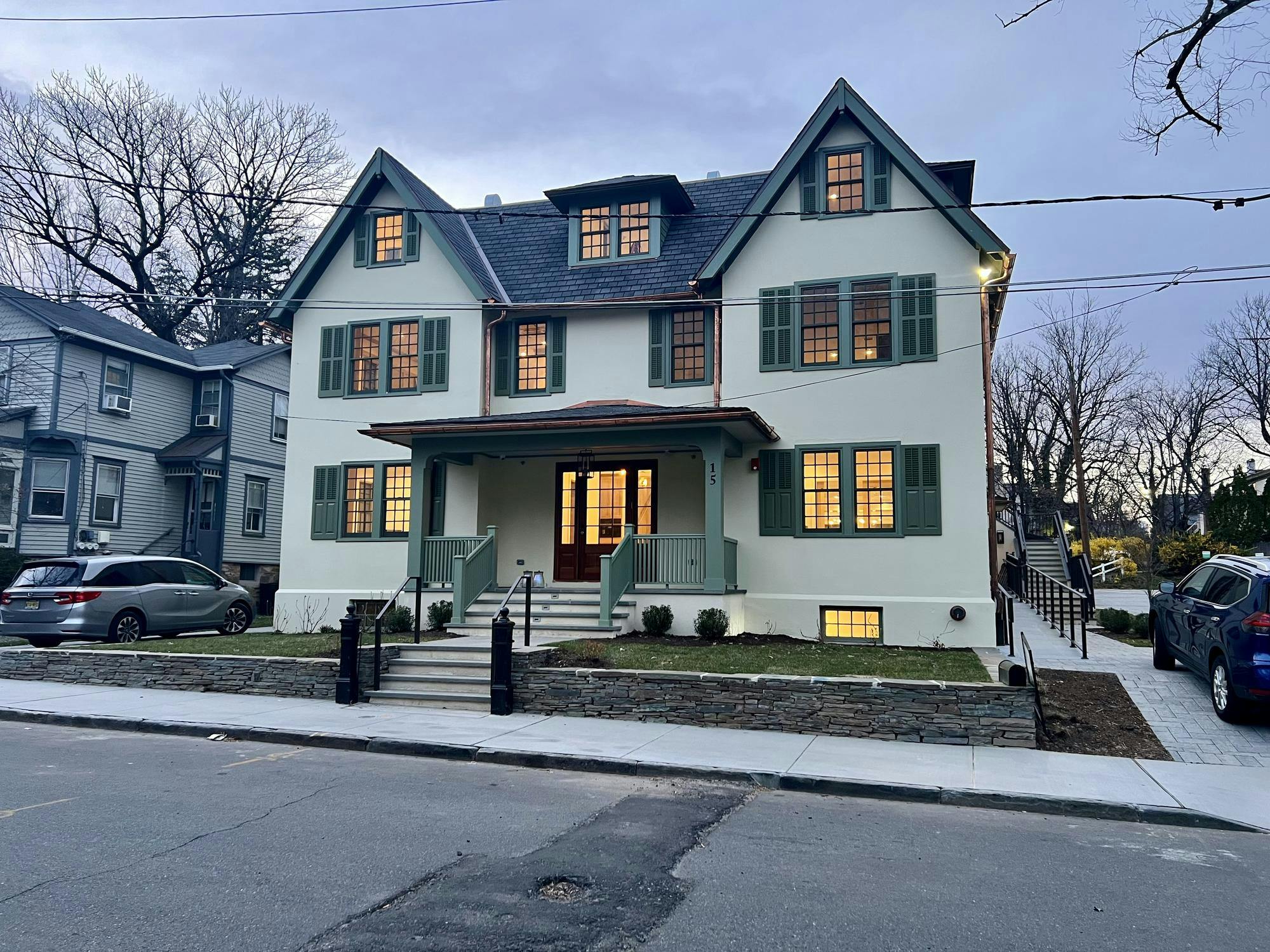 A three-story building with beige walls and green shutters stands at the corner of two streets.