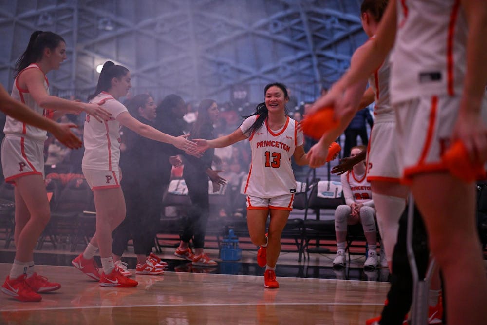 Female basketball player running out to high fives from other basketball players.