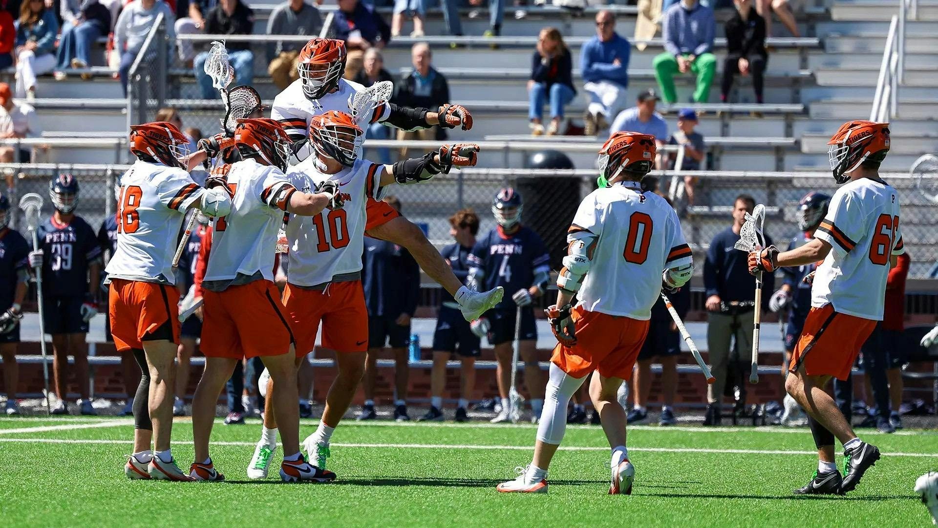 Princeton men’s lacrosse players celebrate on the field during a game against Penn.