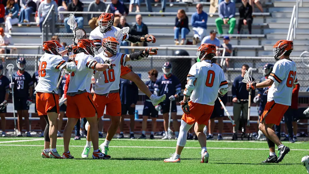 Princeton men’s lacrosse players celebrate on the field during a game against Penn.