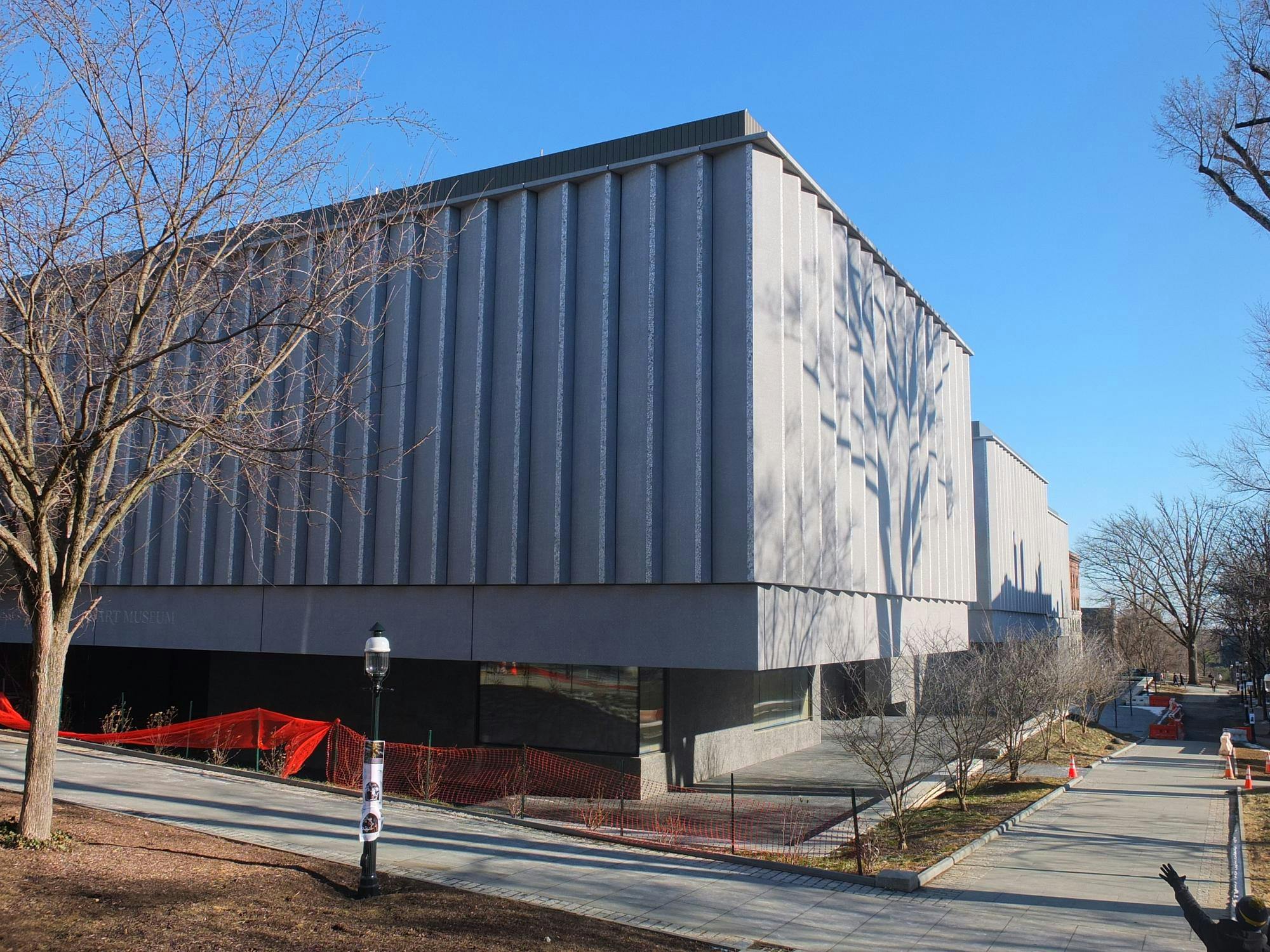 Corner of a grey rectangular building with a silhouette of a tree on one of its sides