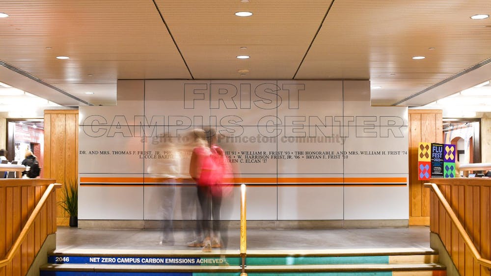 Long exposure photograph of students walking in front of the name "Frist Campus Center".