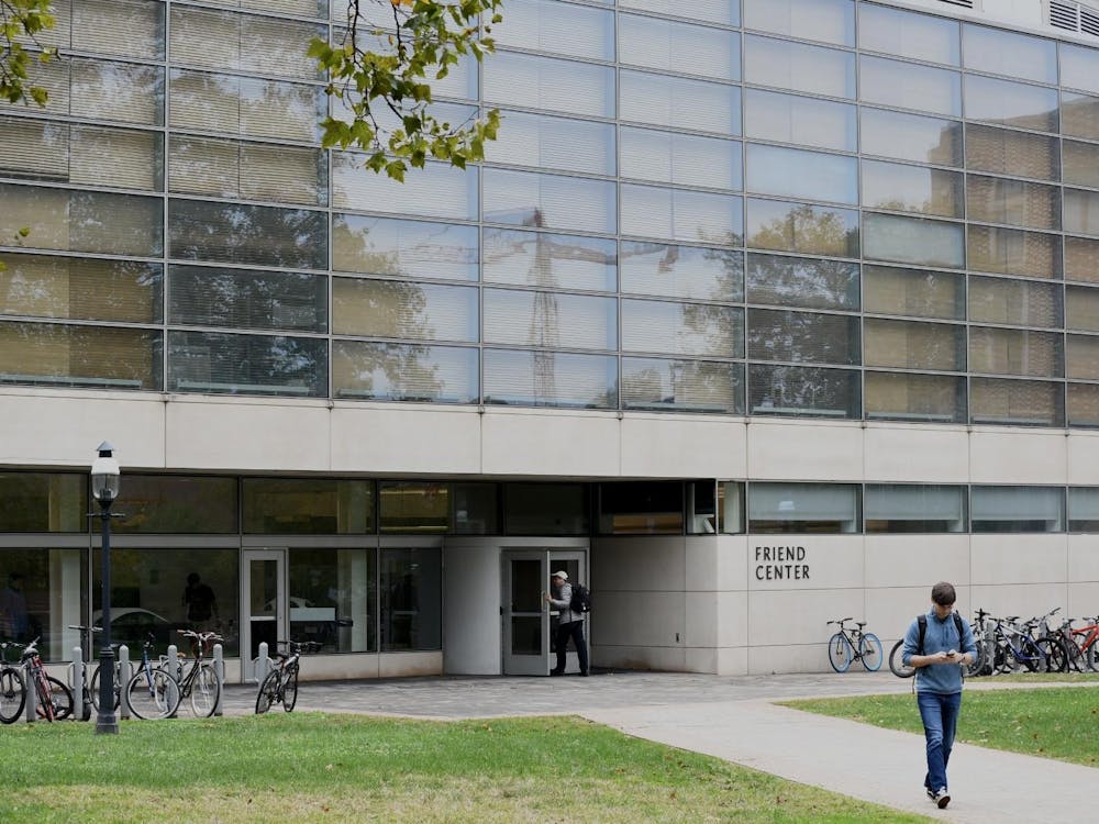 Students walking in front of a concrete building with large windows.