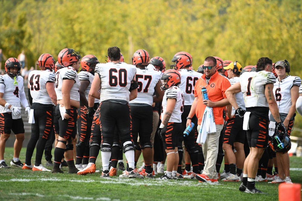 group of players in white and orange uniforms stand on sidelines