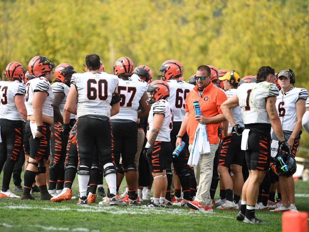 group of players in white and orange uniforms stand on sidelines