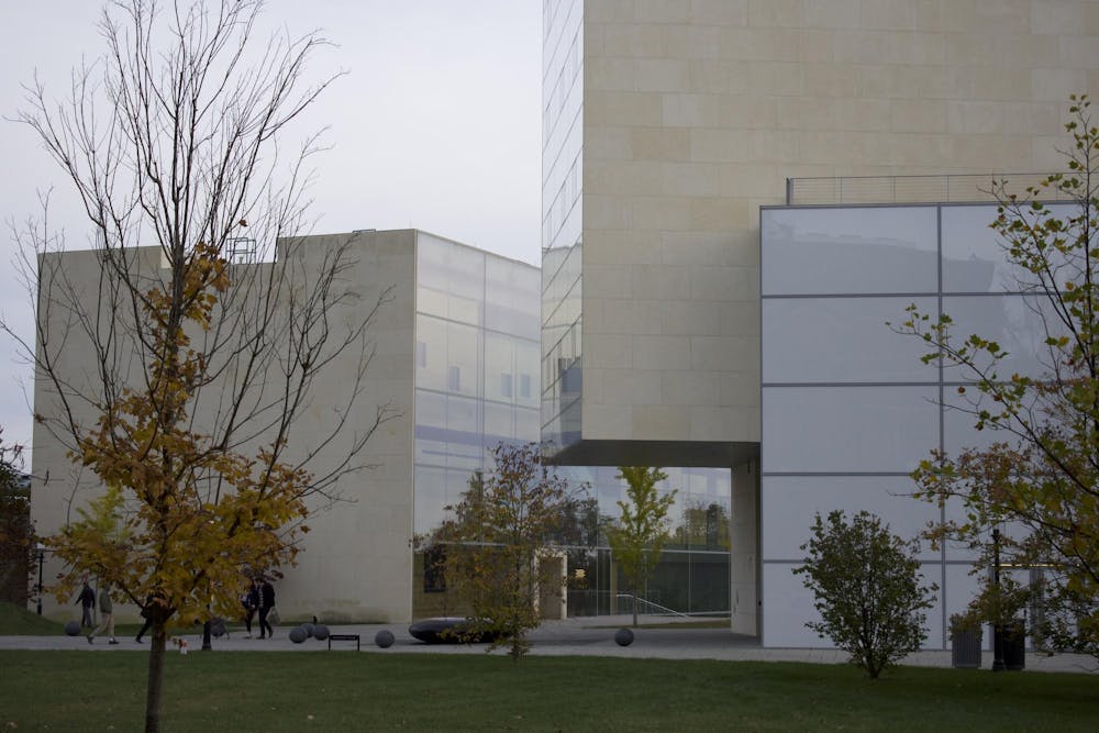 A complex of white, avant-garde buildings with lots of windows sit in a courtyard. 