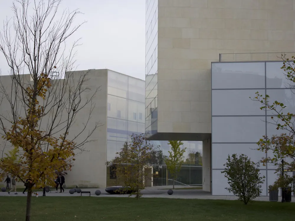 A complex of white, avant-garde buildings with lots of windows sit in a courtyard.