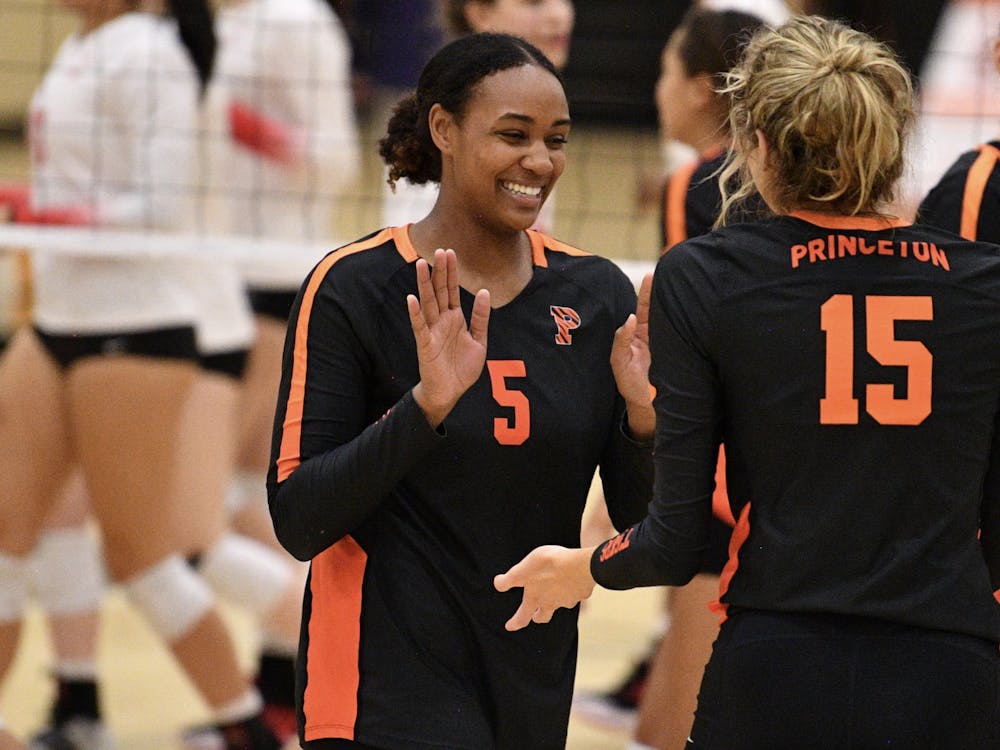 Two women's volleyball players high five with both hands on court