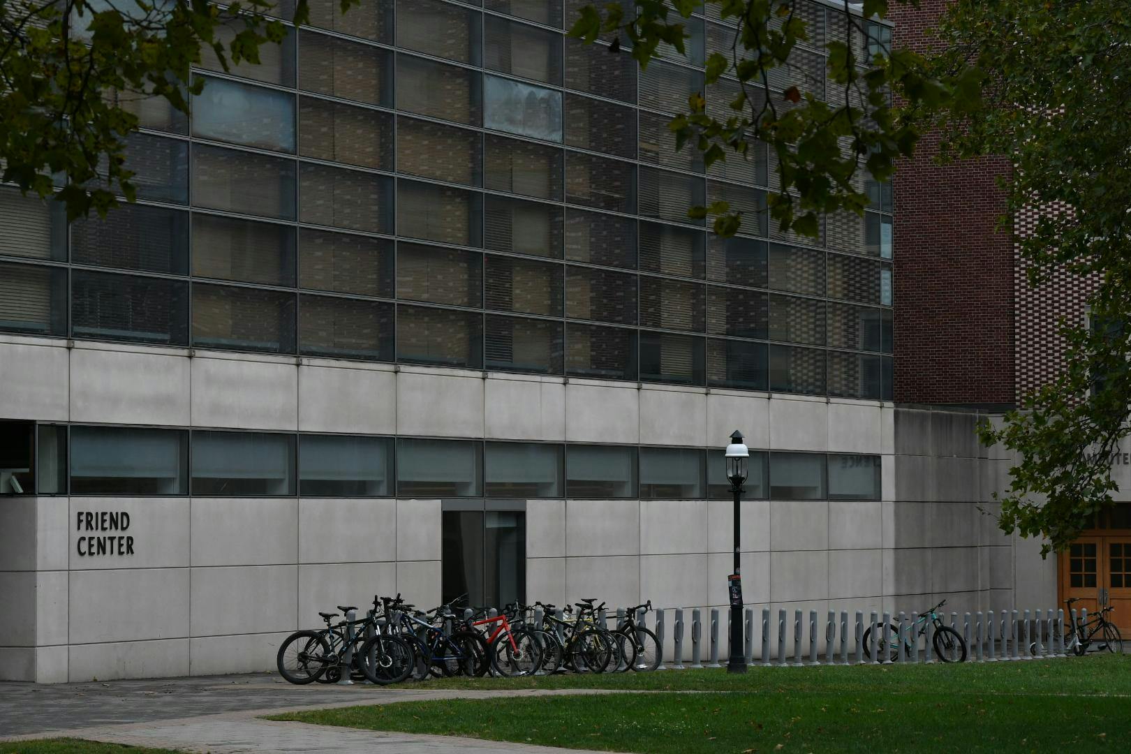 A gray building with black windows above. In the foreground, green grass. On the left, in black text: FRIEND CENTER.