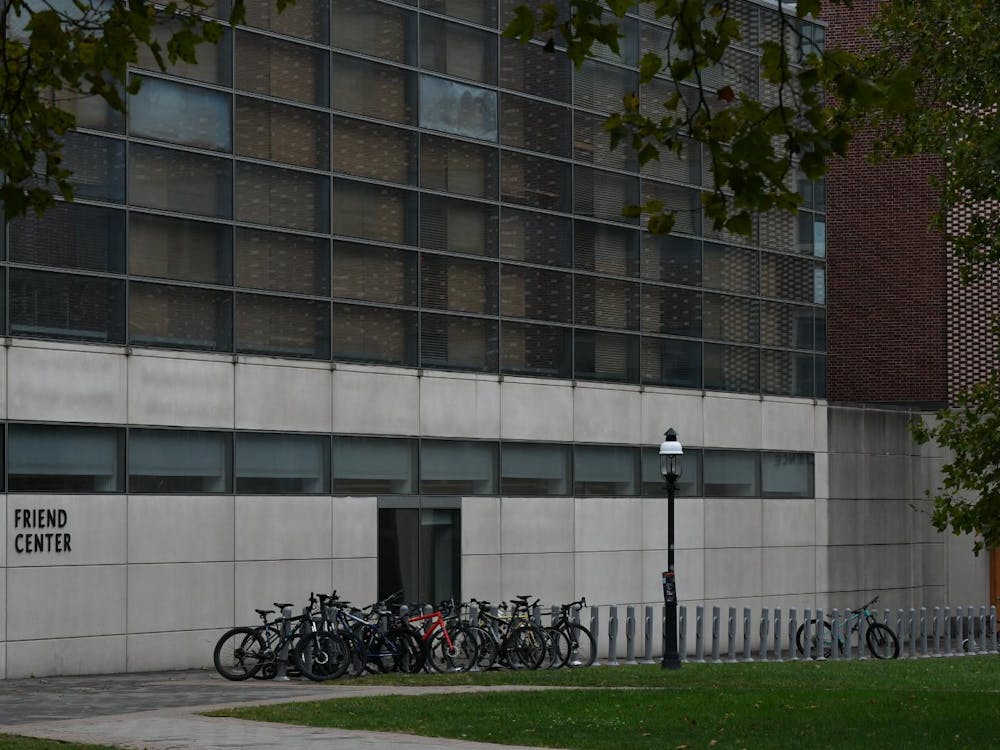 A gray building with black windows above. In the foreground, green grass. On the left, in black text: FRIEND CENTER.