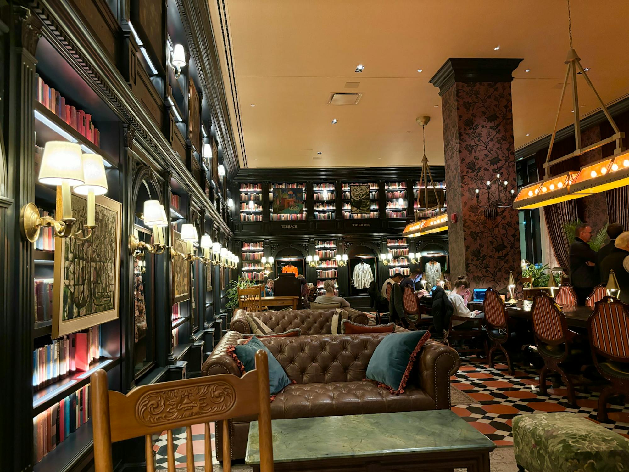 A lounge filled with brown leather couches, bookshelves decorated with Princeton memorabilia, and long tables with ornate chairs. 