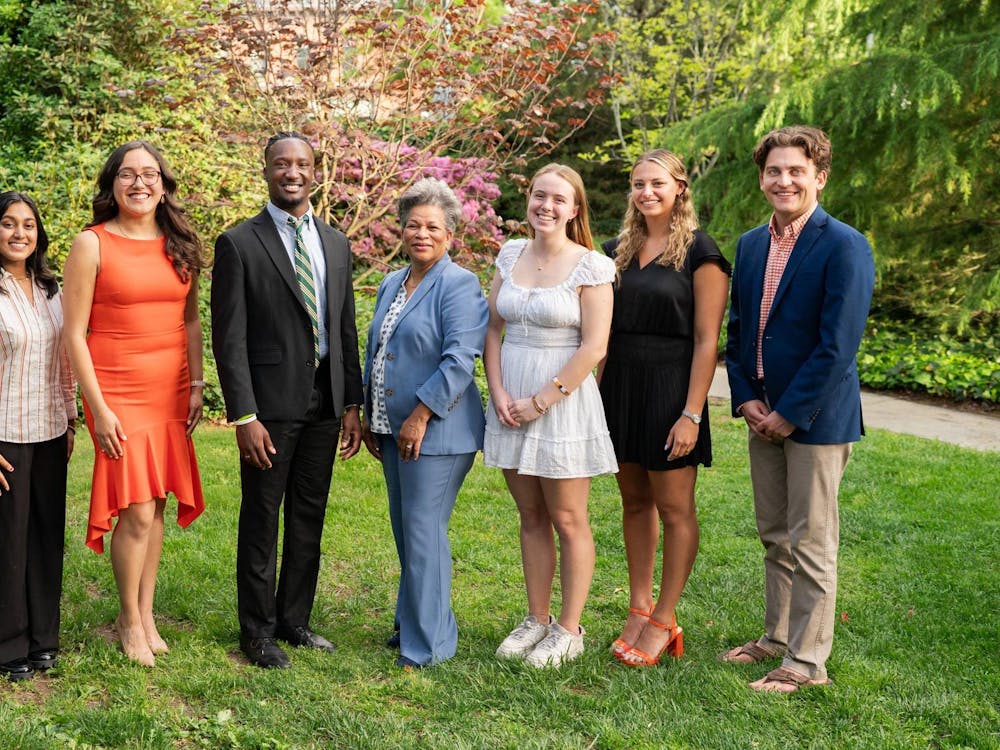 Eight people standing on grass, professionally dressed for a photo.