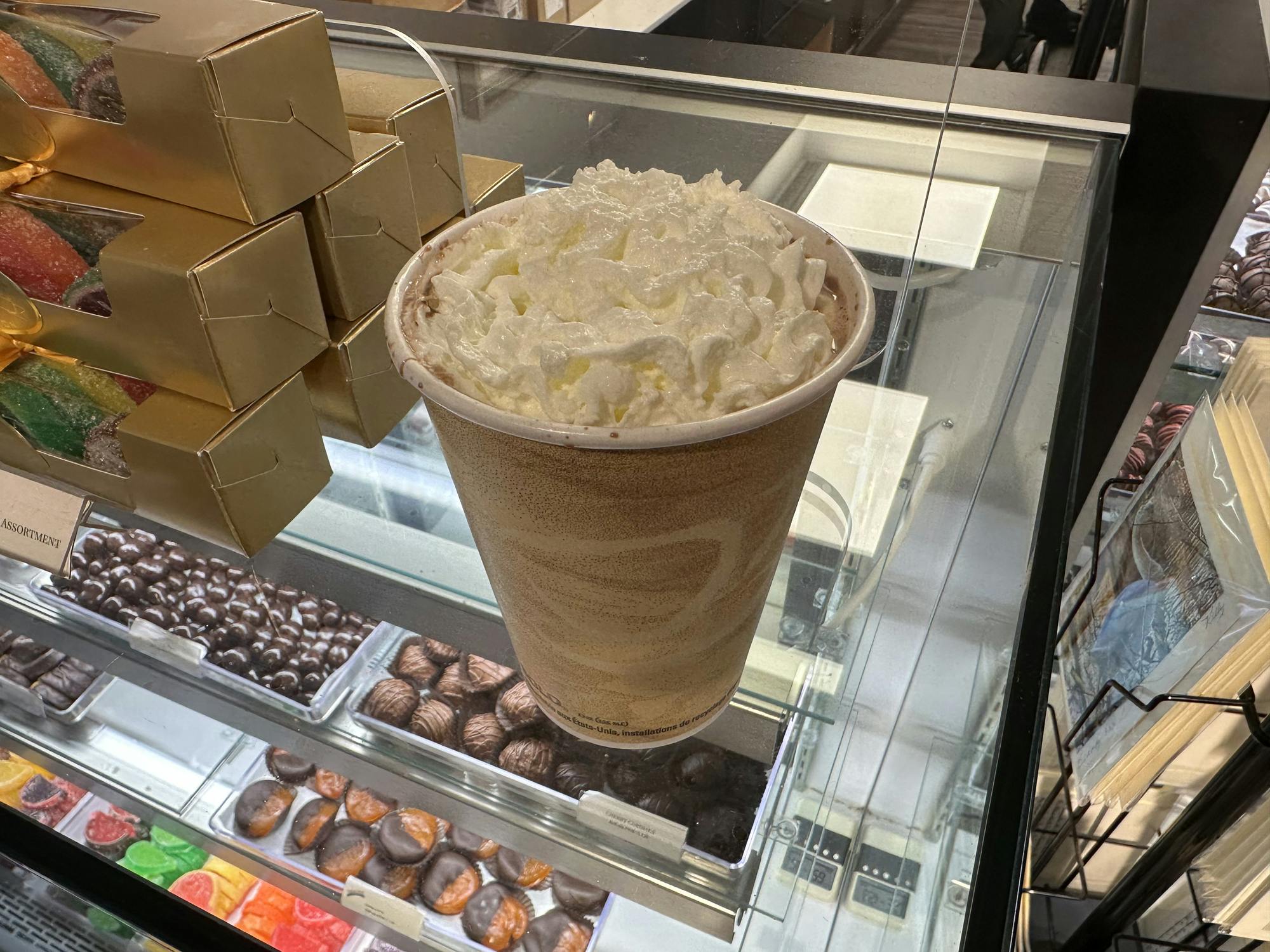 A tall cup of hot chocolate and dollop of whipped cream rests on the counter.