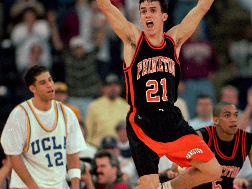 Photograph of Princeton basketball player, Mitch Henderson ’98, in his uniform, jumping in the air with a UCLA basketball player and teammate Sydney Johnson ’97 behind him.