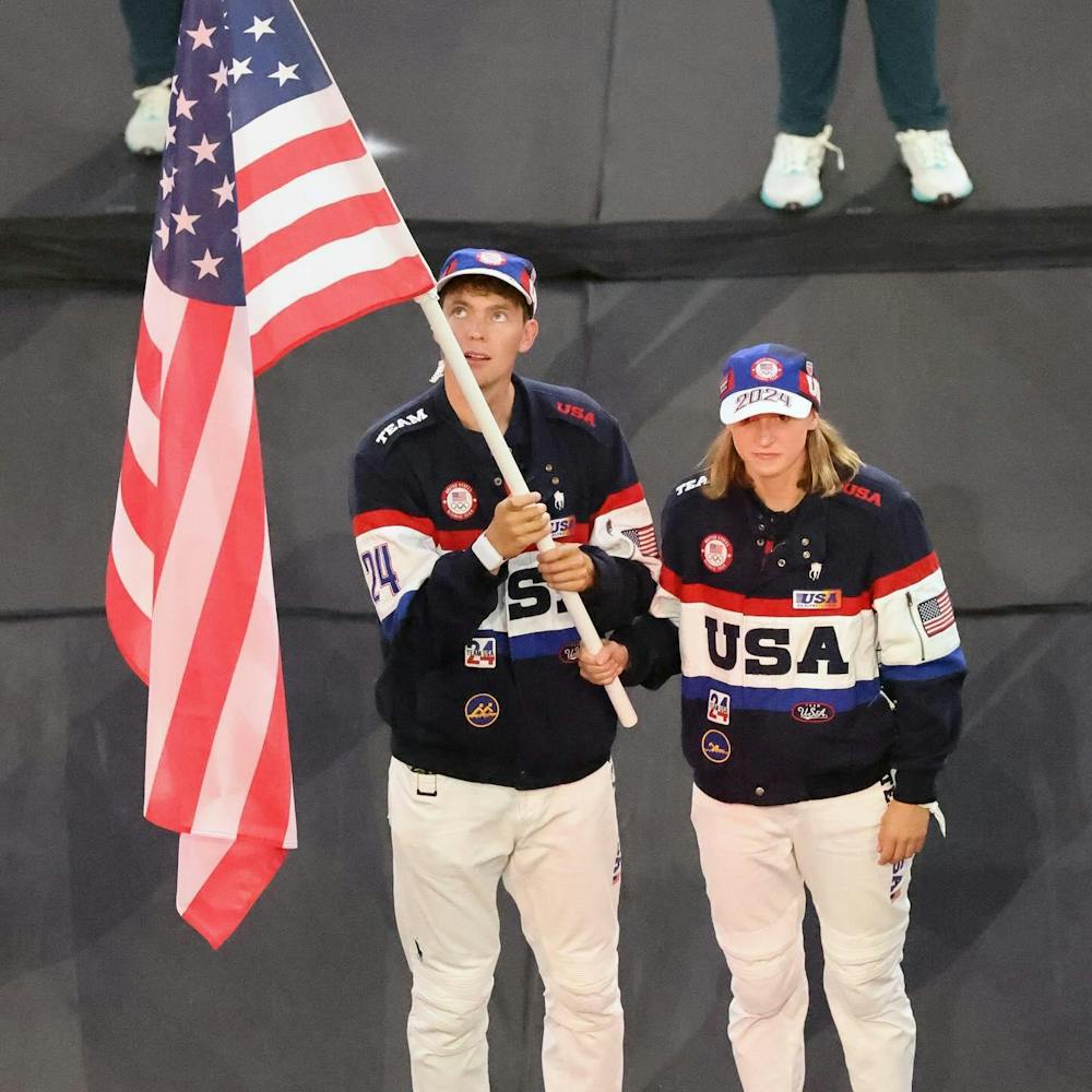 A man and woman dressed in red, white, and blue hold a red, white, and blue flag together.