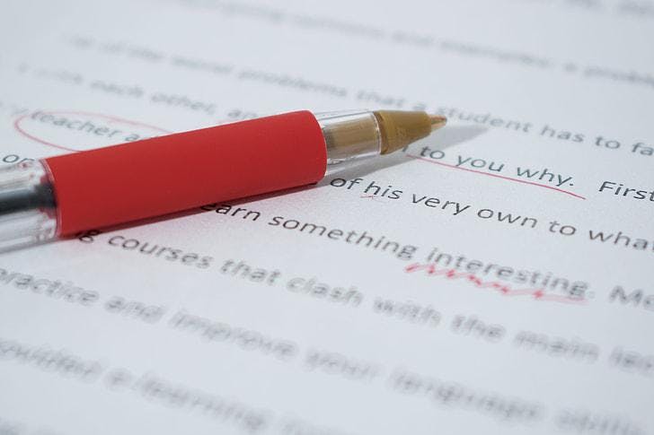 Red pen lying on an essay that has been edited.