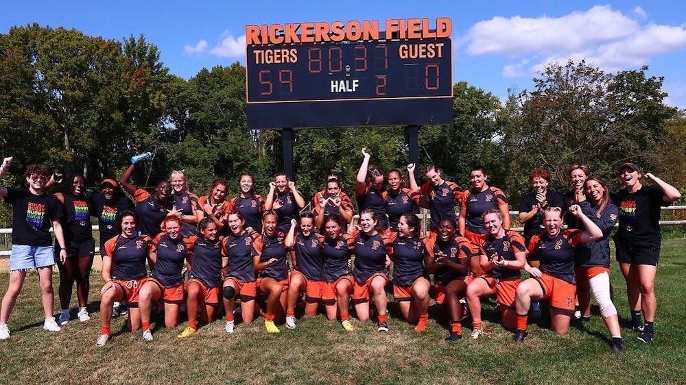 A women’s rugby team celebrates and poses for a picture after a win