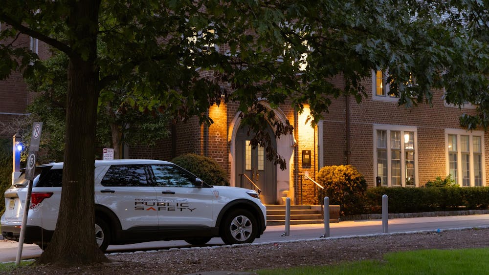 A white truck with the words "public safety" painted on its side is parked in front of McCosh Health Center, a red brick building, in the early evening.