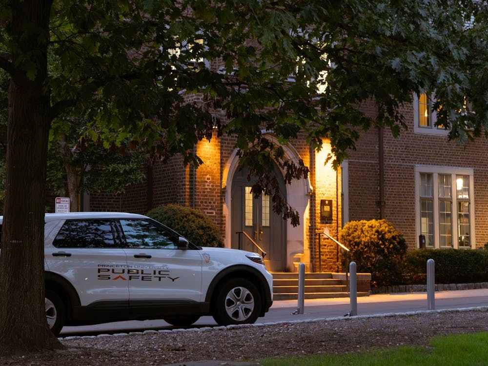 A white truck with the words "public safety" painted on its side is parked in front of McCosh Health Center, a red brick building, in the early evening.