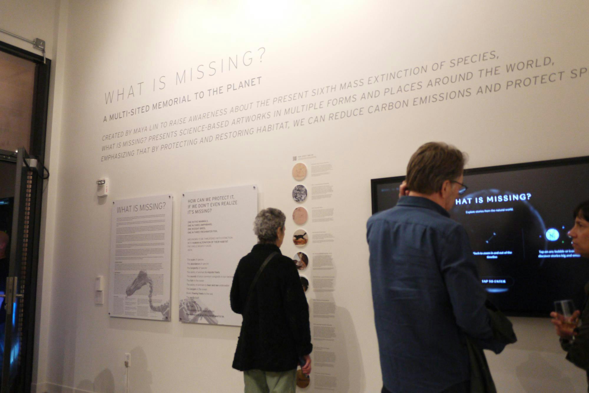 Attendees look at a white wall in an exhibit