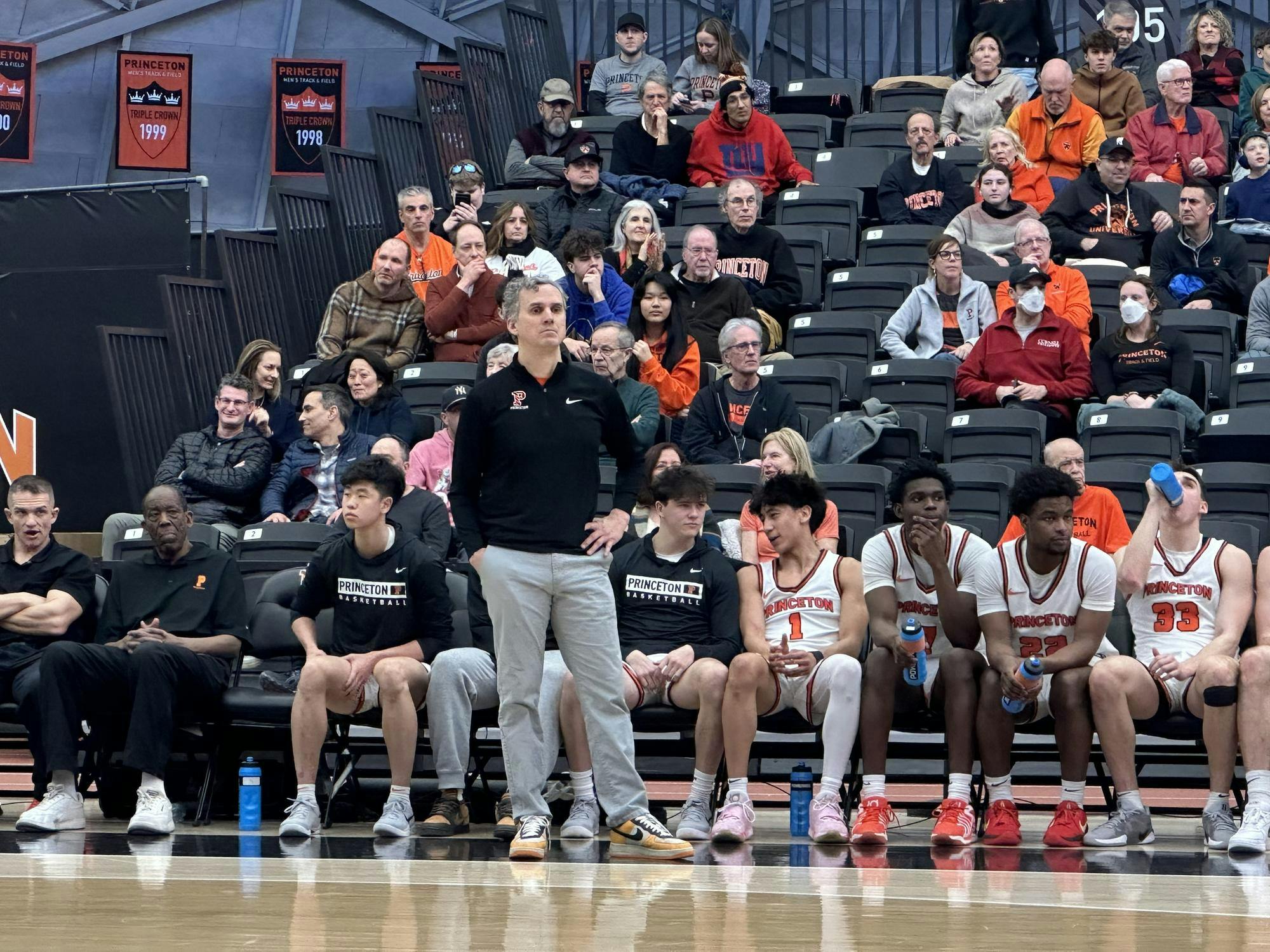 Basketball coach standing in front of bench of players on a court.