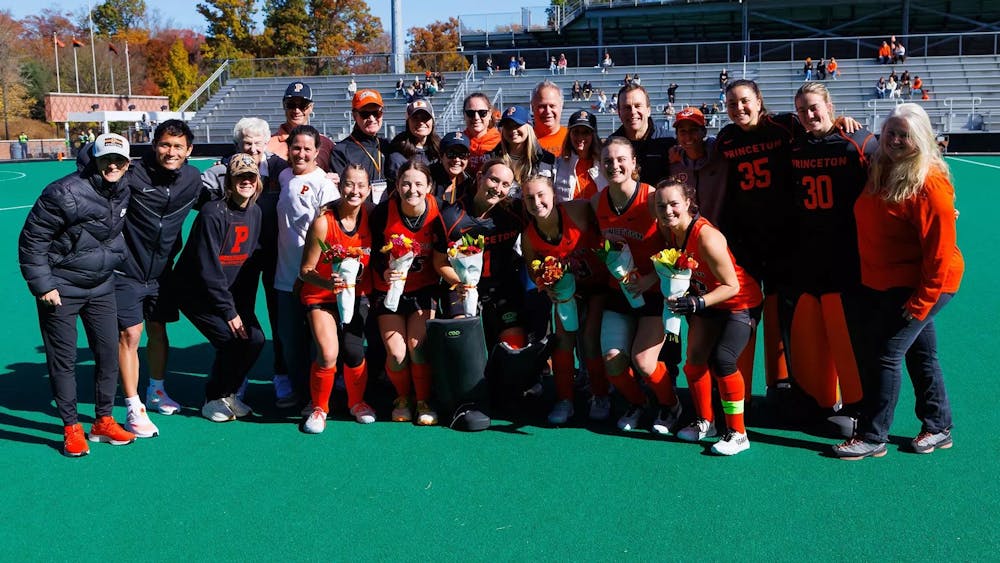 Large group of people standing for photo on field hockey pitch.