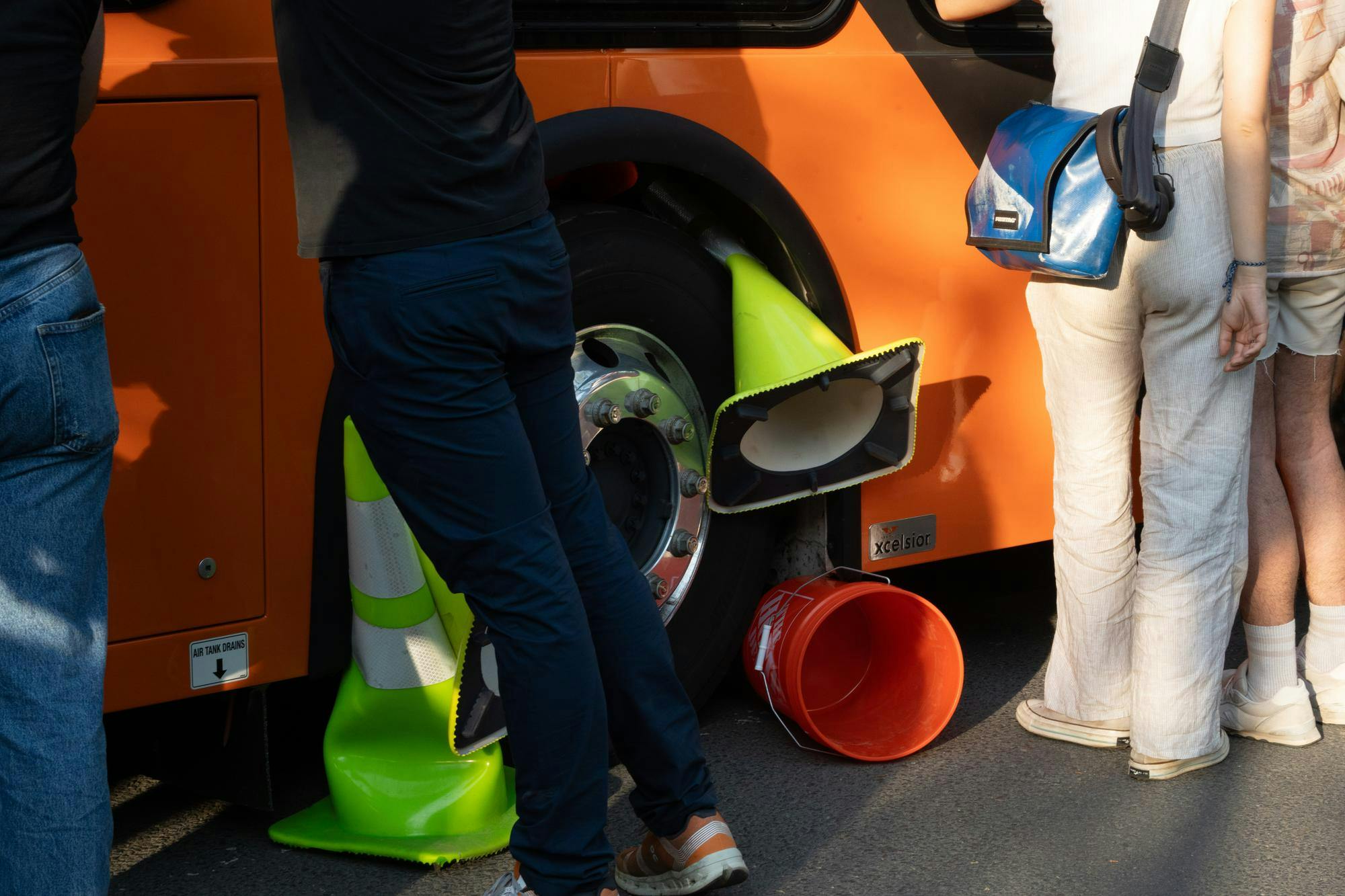 The wheel of a bus is impeded by several cones and buckets. 