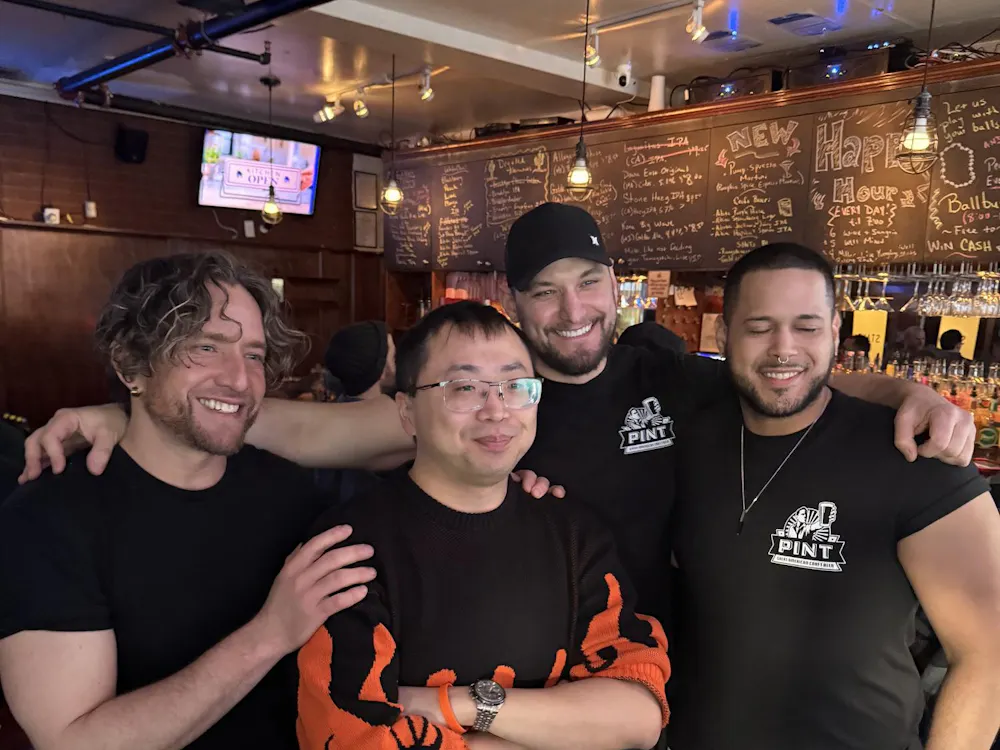 Four men stand at a bar.