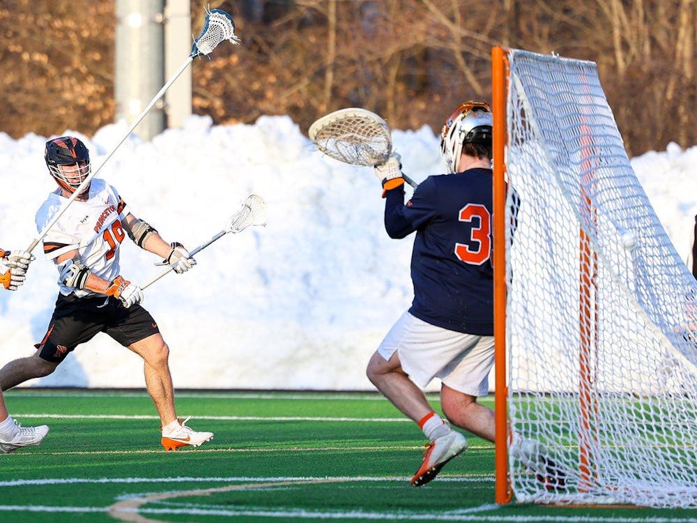 Princeton lacrosse player in white jersey shoots and scores against Syracuse goalie in navy and orange jersey.
