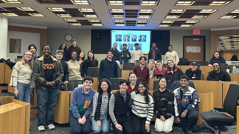 The members of the 2025 Undergraduate Student Government standing happily around in Robertson Hall following their last meeting of the semester.